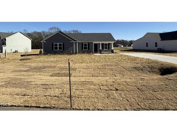 Charming one-story home featuring gray siding, black shutters, covered entry, and a well-manicured lawn at 44 Harvest Hills Ln, Dunn, NC 28334