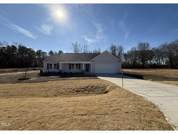 Charming one-story home features a manicured lawn and inviting front porch, with an attached two-car garage at 73 Phil Jack Rd, Dunn, NC 28334
