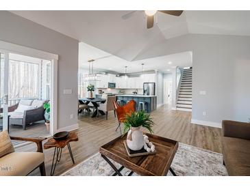 Open-concept living room with modern decor, leading to a spacious kitchen and a screened-in porch at 749 Bowden Rd, Chapel Hill, NC 27516