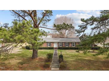 Charming single-story brick home with mature landscaping and a well-manicured front lawn at 102 Trinity Dr, Elon, NC 27244