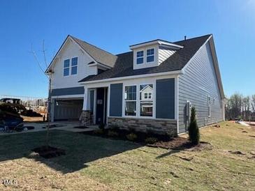 New home showing gray siding, stone accents, a two-car garage, and a well-maintained lawn at 121 Willow Cameron Way, Angier, NC 27501