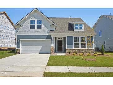 Charming, two-story home featuring a 2-car garage, landscaped yard, and a mix of stone and siding accents at 121 Willow Cameron Way, Angier, NC 27501
