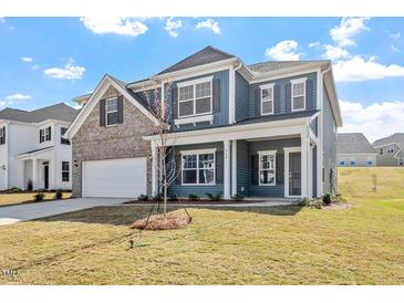 Charming two-story home with blue siding, brick accents, and a well-manicured lawn on a sunny day at 319 N Maple Walk # 213, Garner, NC 27529