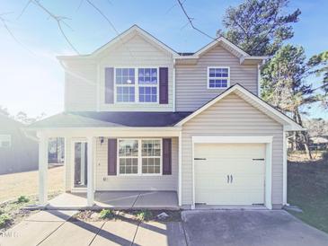 Charming two-story home featuring a covered porch, attached garage and neutral siding against a bright blue sky at 543 Camel St, Clayton, NC 27520