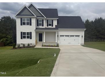 Charming two-story home with a two-car garage, a well-manicured lawn, and dark shutters against the light siding at 122 Reece Dr, Sanford, NC 27332