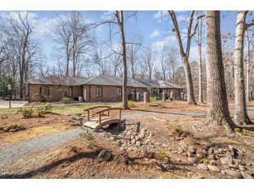 Stunning single-story brick home with beautiful landscaping and a charming bridge feature at 221 Saddle Ridge Rd, Chapel Hill, NC 27514