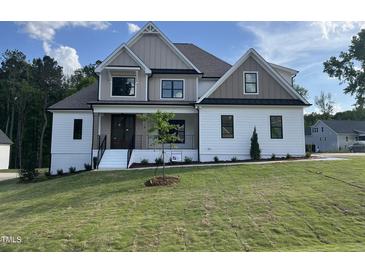 Charming two-story home featuring a modern design with a landscaped yard, complemented by blue skies and a manicured lawn at 318 Deer Tail Ln # 35, Fuquay Varina, NC 27526