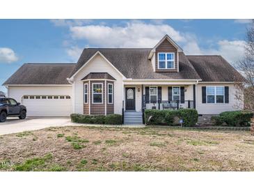 Charming home featuring a cozy front porch, well-maintained landscaping, and a convenient attached two-car garage at 47 London Ln, Angier, NC 27501