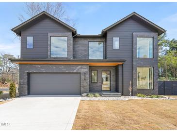 Modern two-story home featuring a gray brick and siding exterior, large windows, and attached garage at 838 Woodburn Rd, Raleigh, NC 27605
