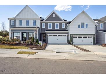Modern townhomes with neutral siding and a two-car garage sit on a tree-lined street at 917 Montague Ave, Durham, NC 27703