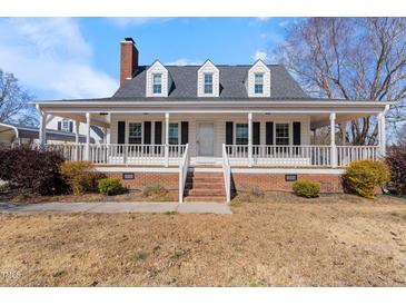 Home's exterior features a charming front porch and meticulously manicured landscaping at 20 Jenmar Dr, Fuquay Varina, NC 27526