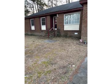 A charming single-story brick home with red trim, surrounded by a lawn that requires refreshing at 208 Essex Rd, Nashville, NC 27856