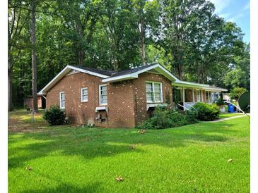 Charming brick home nestled on a lush green lawn, surrounded by mature trees, creating a peaceful and private setting at 323 Ranch Farm Rd, Raleigh, NC 27603
