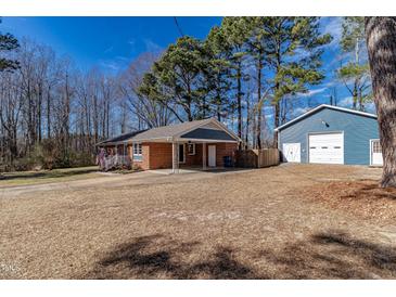 Cozy brick home featuring a detached blue garage and a large driveway, with a well-manicured lawn at 388 Holland Dr, Smithfield, NC 27577
