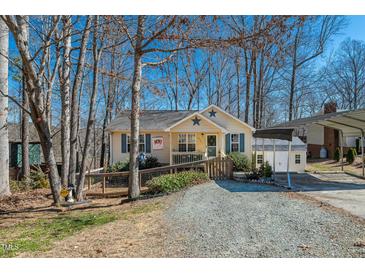 Charming one-story home featuring a cozy porch, a gravel driveway, and a convenient carport on a sunny day at 4901 North Pointe, Sanford, NC 27332