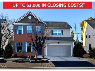 Charming two-story home featuring brick facade, blue shutters, and an attached two-car garage at 508 Stapleford Ln, Fuquay Varina, NC 27526