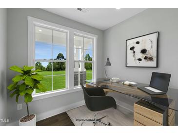 Bright office space with a modern glass desk and large windows overlooking the green landscape at 54 Merle Dr, Wendell, NC 27591