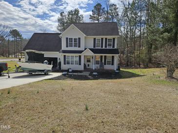 Charming two-story home with black shutters, attached garage, and boat parked in the driveway at 1201 Teakwood Ct, Sanford, NC 27330