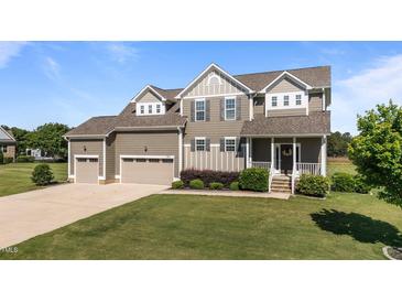 Charming two-story home with a manicured lawn and a three-car garage on a sunny day at 124 Brookstone Way, Angier, NC 27501