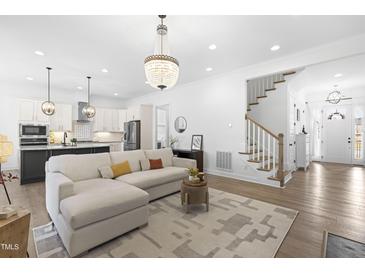 Bright living room featuring a chandelier, an area rug, and hardwood floors at 124 Ferrell W Rd, Apex, NC 27523