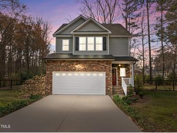Charming two-story home featuring stone accents, attached two-car garage, and landscaped front yard at 1404 Vanguard Pl, Durham, NC 27713
