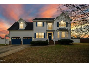Charming two-story home with blue shutters, a two-car garage, and a beautifully landscaped front yard at dusk at 1421 Harvey Johnson Rd, Raleigh, NC 27603