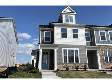 Charming, new construction two-story home with stone accents, a quaint porch, and vibrant blue front door at 1573 Wendell Valley Blvd, Wendell, NC 27591