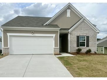 Charming one-story home with brick and vinyl siding, a two-car garage, and a well-manicured lawn at 209 Swift Park Dr, Zebulon, NC 27597