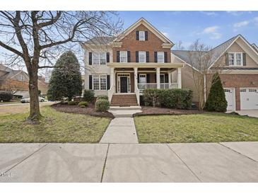 Charming brick two-story home with a welcoming front porch and landscaped yard at 310 Millsfield Drive Dr, Cary, NC 27519