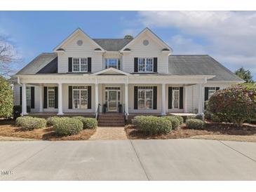 Beautiful white two-story home with black shutters, large front porch, and landscaped yard at 75 Morgan Dr, Lillington, NC 27546