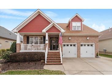Charming two-story brick home with red accents, a cozy front porch, and a well-manicured lawn at 836 Canyoncreek Ln, Fuquay Varina, NC 27526