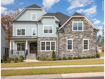 Stunning exterior view of a two-story home with stone accents, manicured lawn, and a welcoming front porch at 123 Stone Park Dr, Wake Forest, NC 27587
