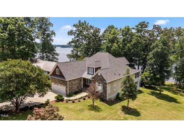 Beautiful stone home featuring a manicured lawn and stunning lake views at 1315 Sagamore Dr, Louisburg, NC 27549