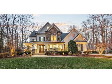 Beautiful two-story home with stone accents and a covered front porch, surrounded by mature trees and a lush lawn at 2617 Jones Ferry Rd, Chapel Hill, NC 27516