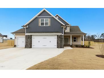 Charming two-story home with a three car garage, stone accents, and a well-manicured lawn on a sunny day at 51 Blackberry Ln, Benson, NC 27504