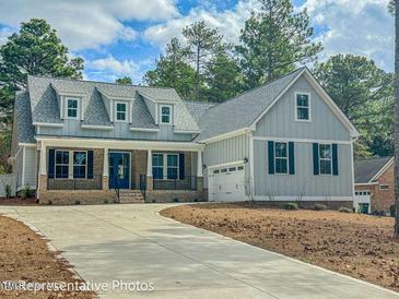 Charming two-story home featuring a well-manicured lawn, blue door, dormer windows, and an attached two car garage at 515 Sanctuary Trl, Cameron, NC 28326