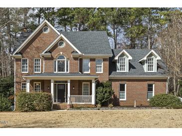 Elegant brick home featuring a covered front porch and well-manicured landscaping at 6108 King Croydon Ct, Raleigh, NC 27603