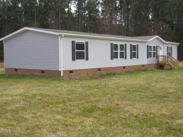 Charming home featuring a mix of gray siding and brick foundation, complemented by black shutters and a natural wooded backdrop at 9115 Nc 157, Rougemont, NC 27572