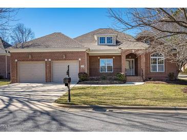Charming brick home featuring an attached two-car garage, manicured lawn, and classic architectural details at 9413 Lake Villa Way, Raleigh, NC 27614