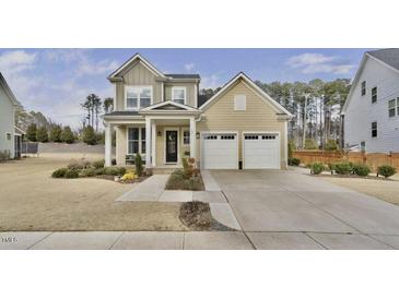 Charming two-story home featuring a covered entryway and a two-car garage with a large concrete driveway at 104 Sage Oak Ln, Holly Springs, NC 27540