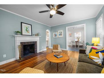 Inviting living room featuring a fireplace, ceiling fan, hardwood floors and comfortable seating at 2511 State St, Durham, NC 27704