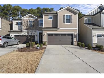 Inviting home featuring a two-car garage, neutral siding, manicured lawn and tree at 3408 Dropseed Dr, Apex, NC 27502