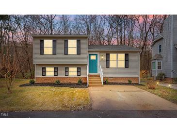 Charming split-level home featuring a quaint front yard, complemented by a vibrant teal-colored front door at 8341 Wynewood Ct, Raleigh, NC 27616