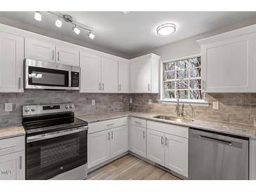 Bright kitchen featuring white cabinets, stainless steel appliances, and modern countertops at 8341 Wynewood Ct, Raleigh, NC 27616