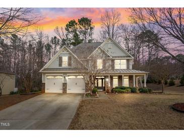 Charming two-story home with a welcoming front porch, three-car garage, and landscaped front yard under a colorful sunset at 94 Fawn Hill Ct, Garner, NC 27529