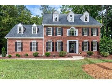 A stately two-story brick home with black shutters and a well-manicured front lawn at 102 Legault Dr, Cary, NC 27513