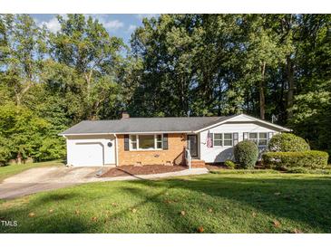 Charming ranch-style home with a brick facade, attached garage, and landscaped front yard at 1224 Manchester Dr, Raleigh, NC 27609