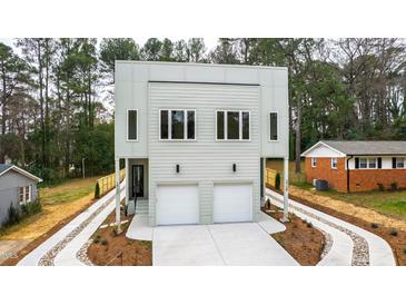 Contemporary home featuring a two-car garage, modern windows, and a landscaped yard with driveway and mulch at 2730 Milburnie Rd, Raleigh, NC 27610