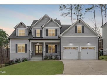 Charming two-story home featuring a manicured lawn, gray siding, dormer windows and a two car garage at 4508 Chandler Creek Pl, Apex, NC 27539