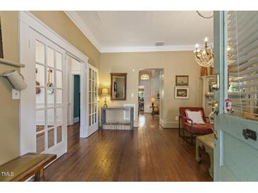 Bright living room featuring hardwood floors, white trim, a chandelier, and glass french doors at 613 S Fuquay Ave, Fuquay Varina, NC 27526